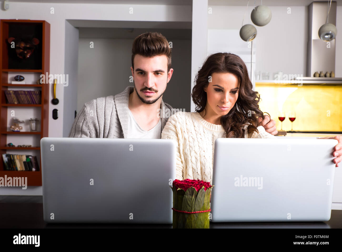A young couple in the evening using their laptop computers at home ...