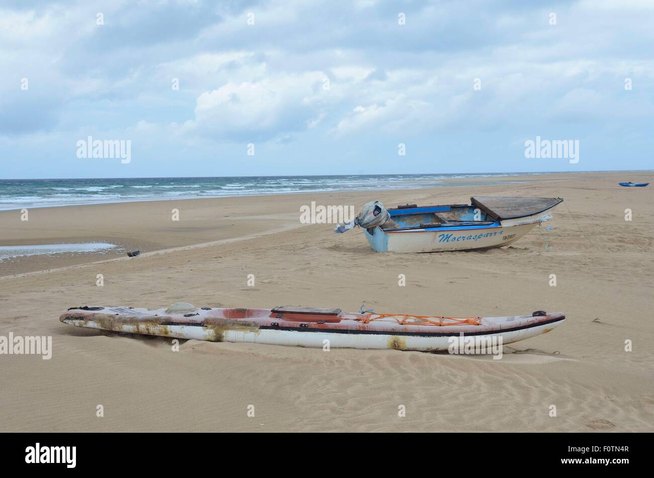 Old dilapidated fishing boats lying on the beach at Inhambane, Mozambique. These are unsafe and home repaired but used daily Stock Photo
