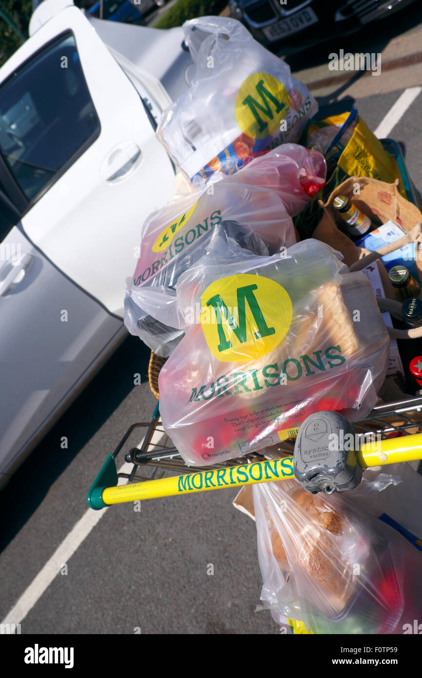 Morrisons supermarket shopping trolley full of shopping bags about to be loaded into a car Stock Photo