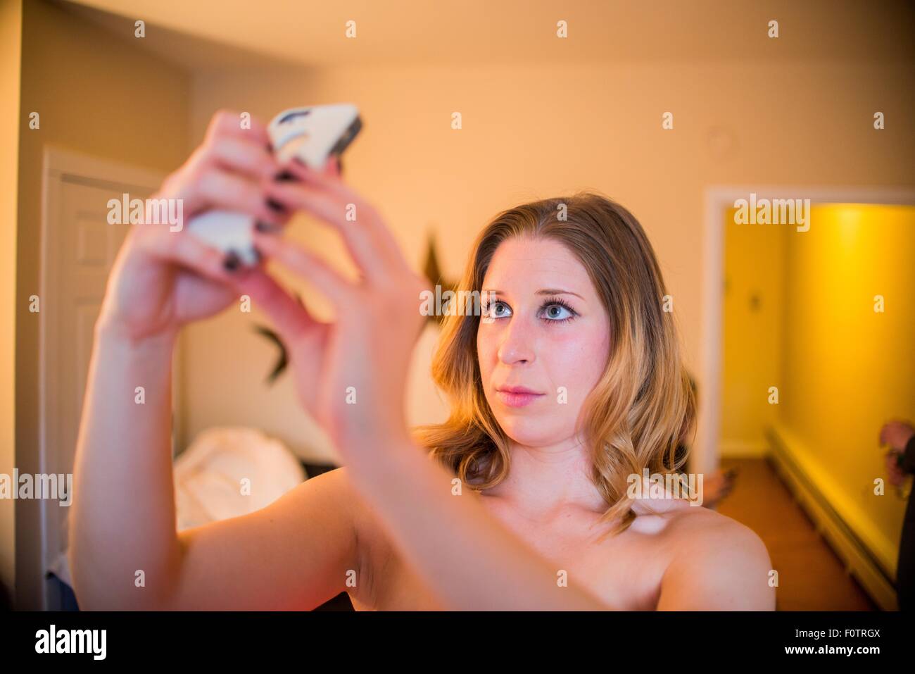 Young woman taking smartphone selfie in hallway Stock Photo