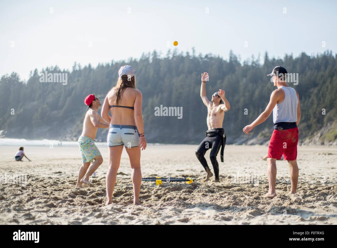 Four adult friends throwing and catching ball on Short Sands Beach, Oregon, USA Stock Photo
