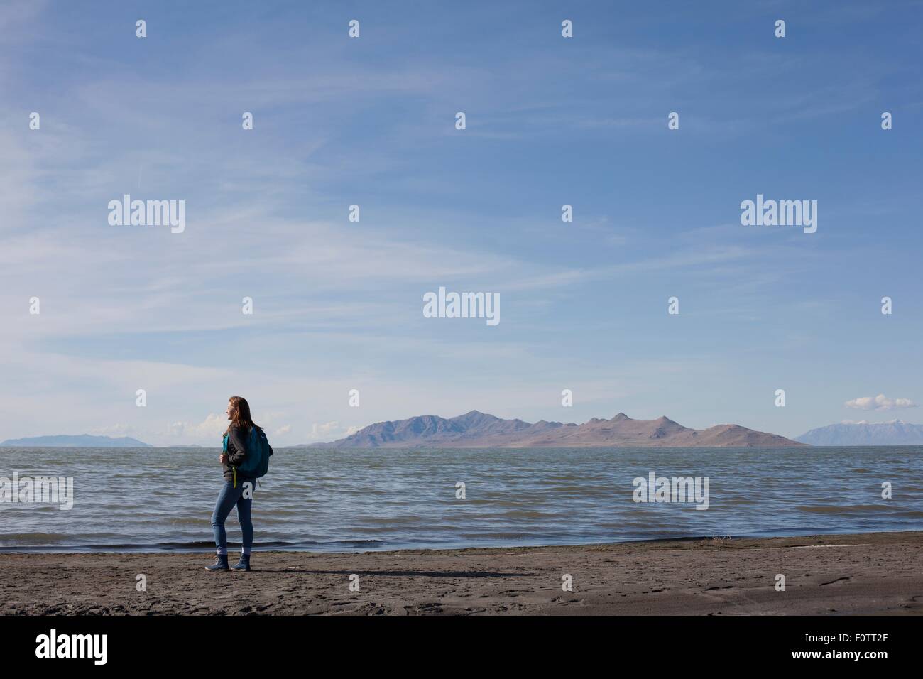 Rear view of young woman standing at waters edge looking out, Great Salt lake, Utah, USA Stock Photo