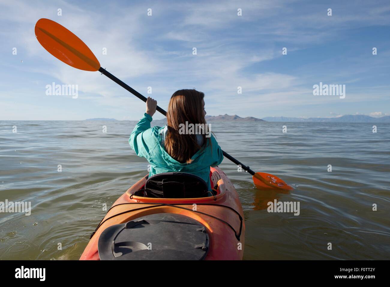 Rear view of young woman kayaking, holding paddles, Great Salt Lake, Utah, USA Stock Photo