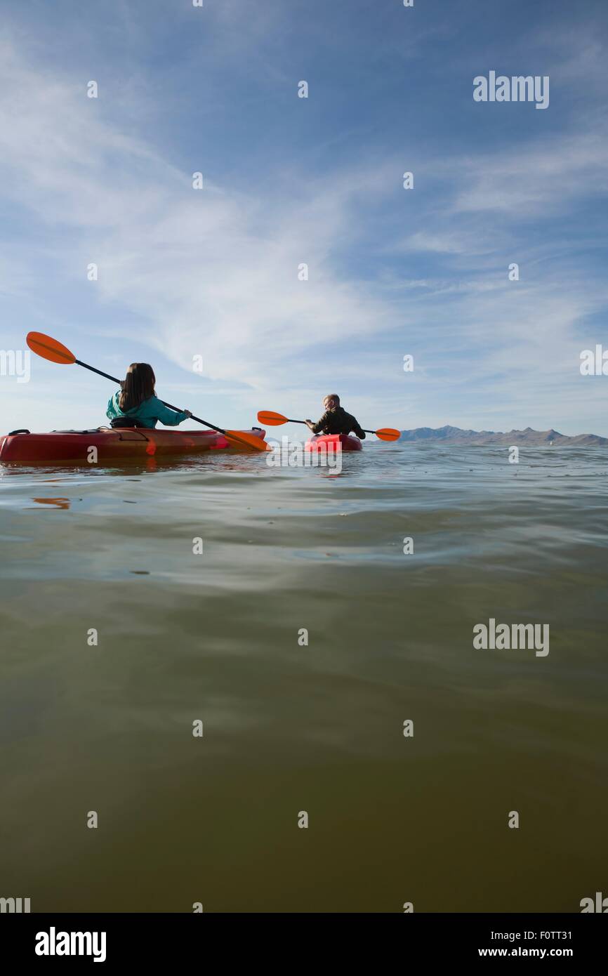 Rear view of young couple in kayaks holding paddles, Great Salt Lake, Utah, USA Stock Photo