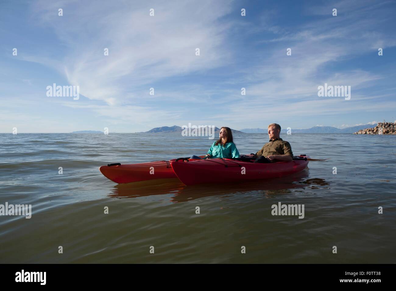 Young couple in kayaks on water, eyes closed looking away, Great Salt Lake, Utah, USA Stock Photo