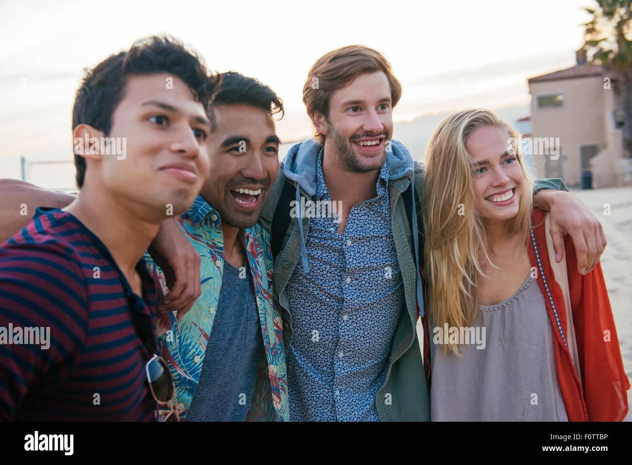 Group of friends standing together on beach, laughing Stock Photo