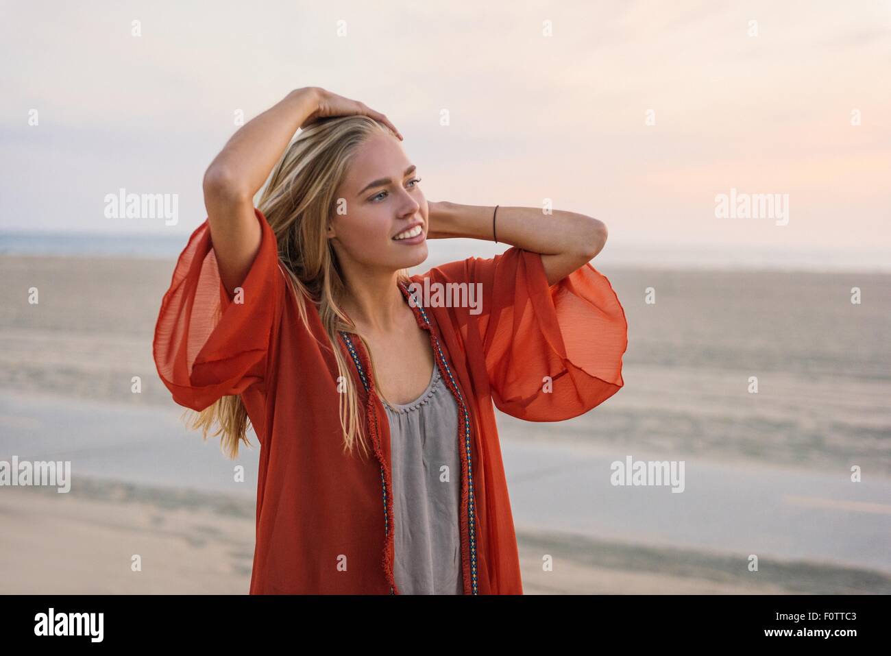 Young woman standing on beach, looking at view Stock Photo