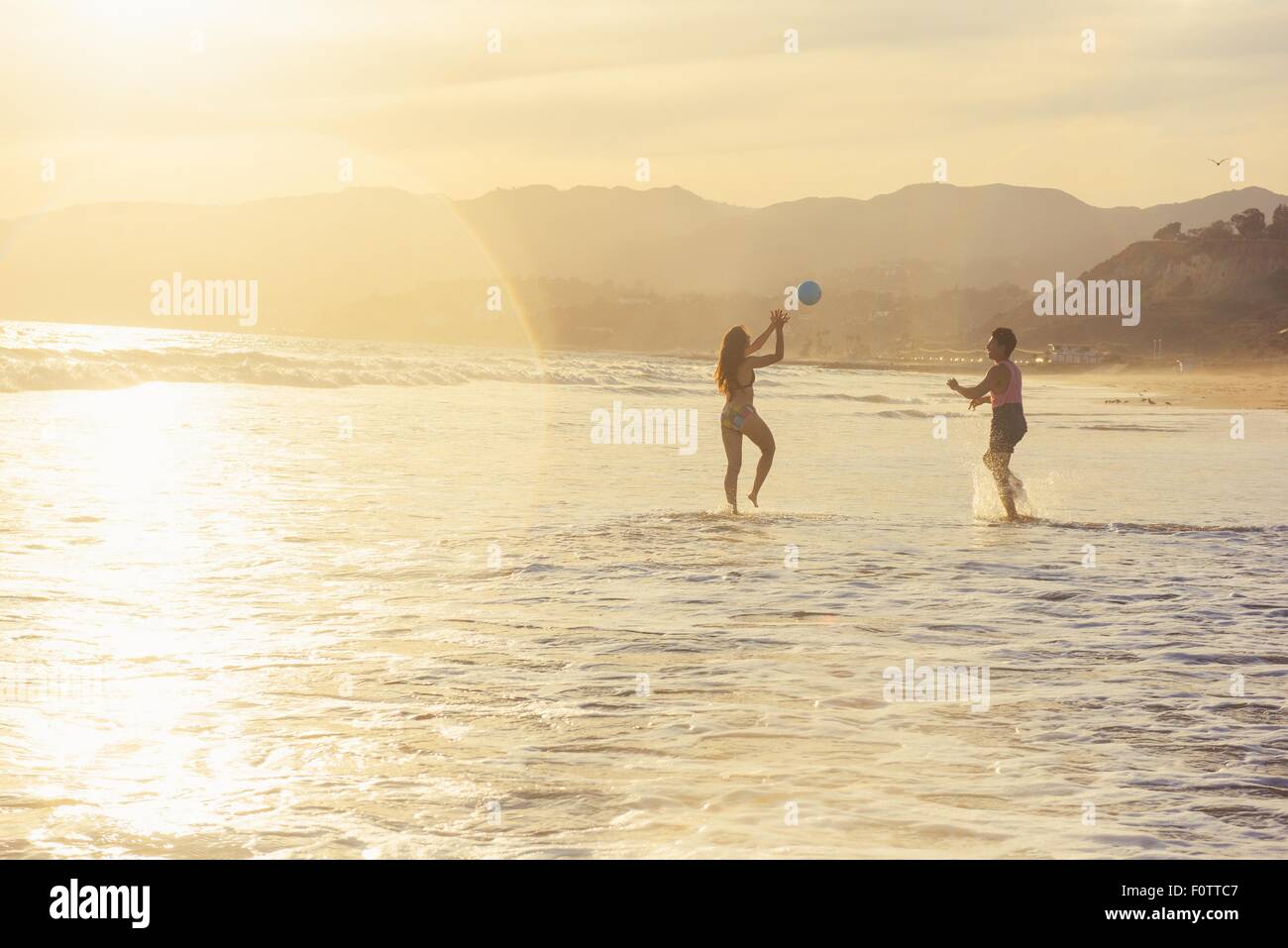 Young couple fooling around on beach, on sea, sunset Stock Photo