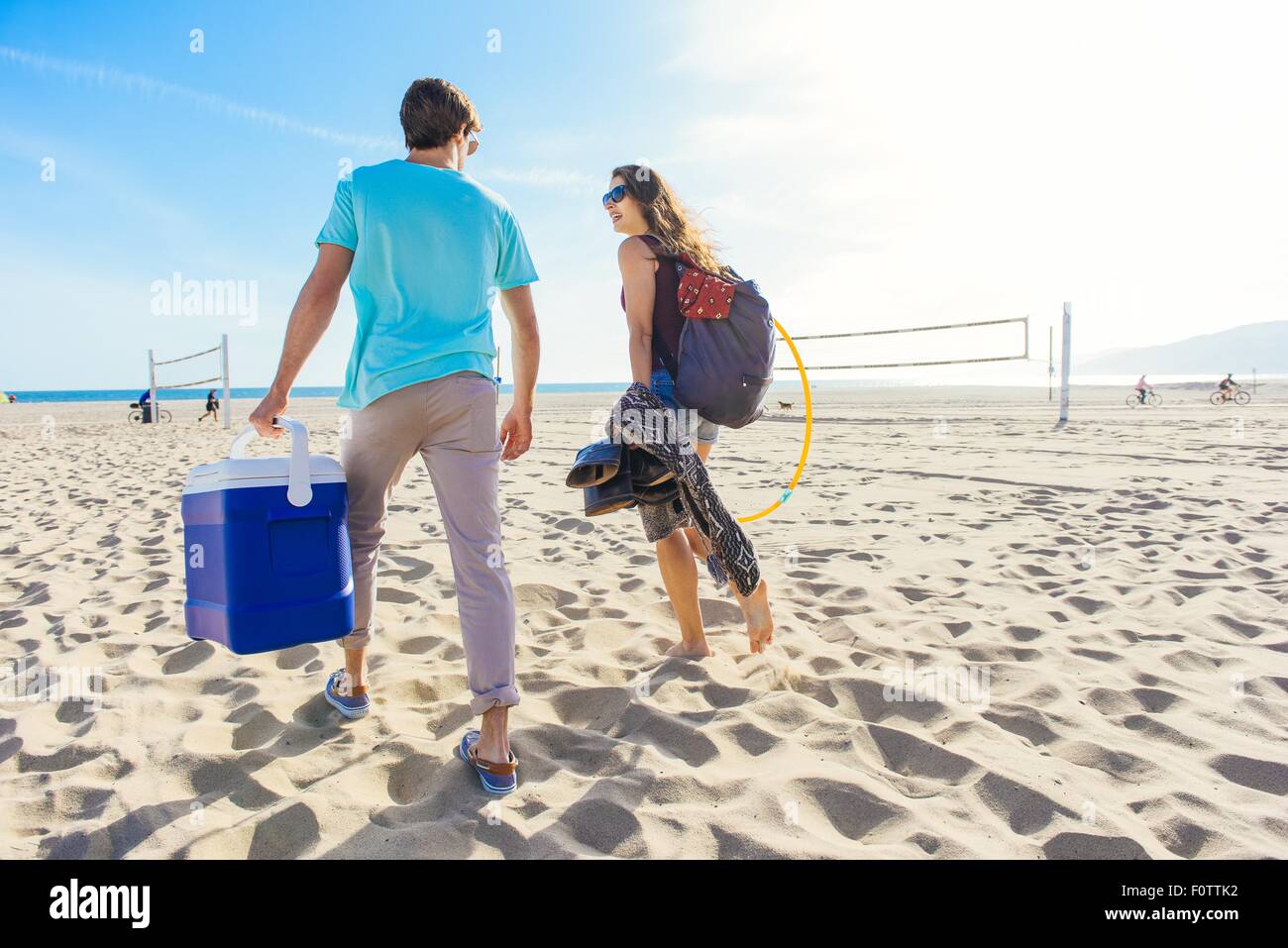 Young couple walking on beach, holding cool box, rear view Stock Photo