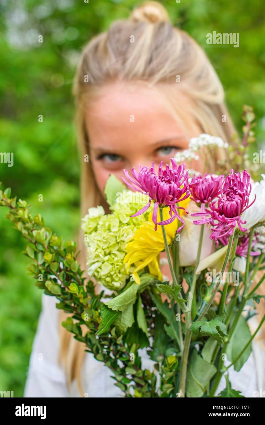 Portrait of young woman behind bunch of flowers Stock Photo