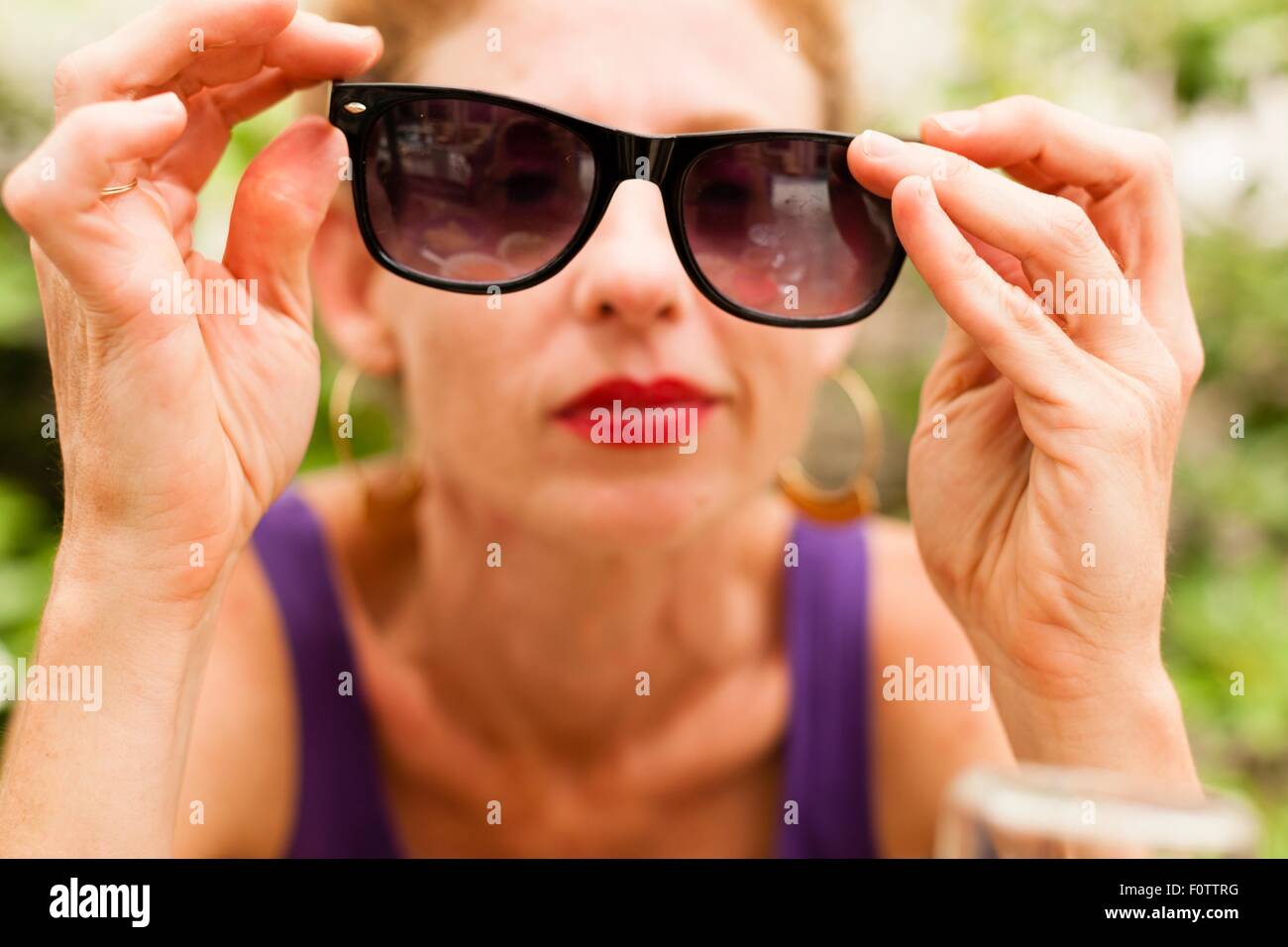 Mid adult woman holding sunglasses in front of her eyes Stock Photo