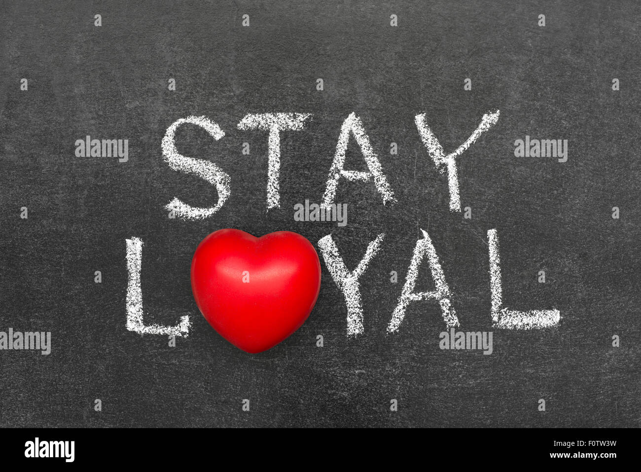 stay loyal phrase handwritten on chalkboard with heart symbol instead of O Stock Photo