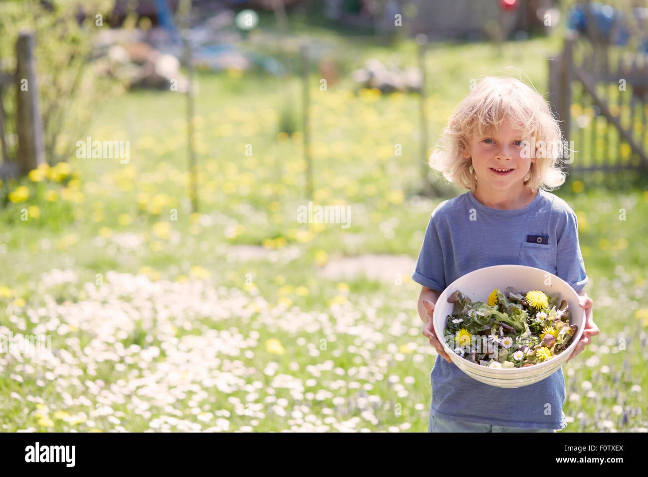 Portrait of young boy holding bowl of garden herbs Stock Photo