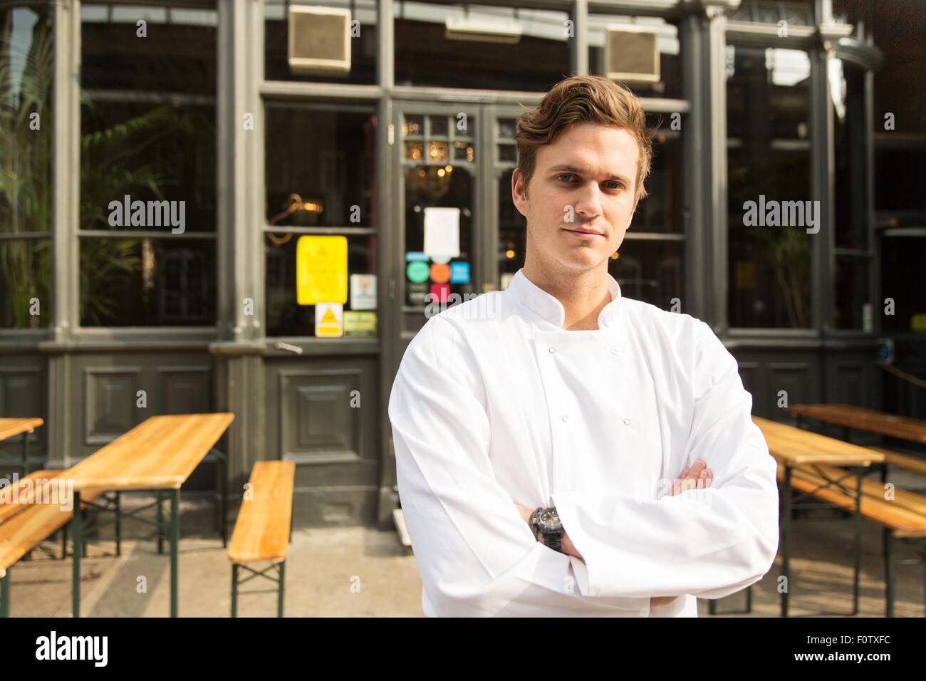 Young chef standing outside of work, arms folded Stock Photo