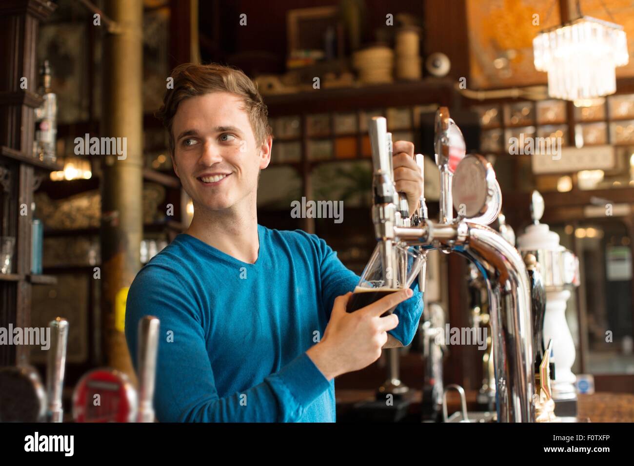 Young man working in public house, serving drink Stock Photo