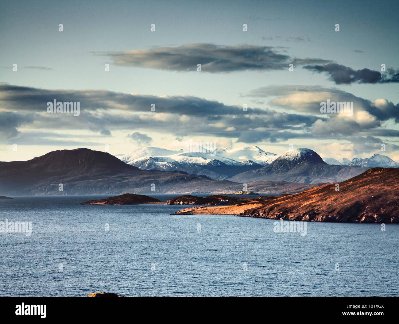 Lake surrounded by snow capped mountains, Assynt, Scotland Stock Photo