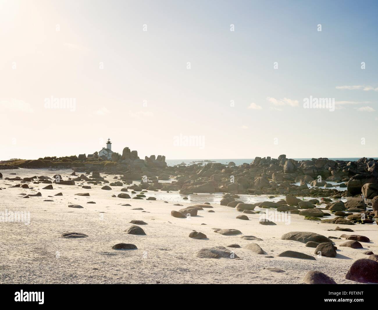 View of beach boulders and lighthouse, Brignogan, Brittany, France Stock Photo