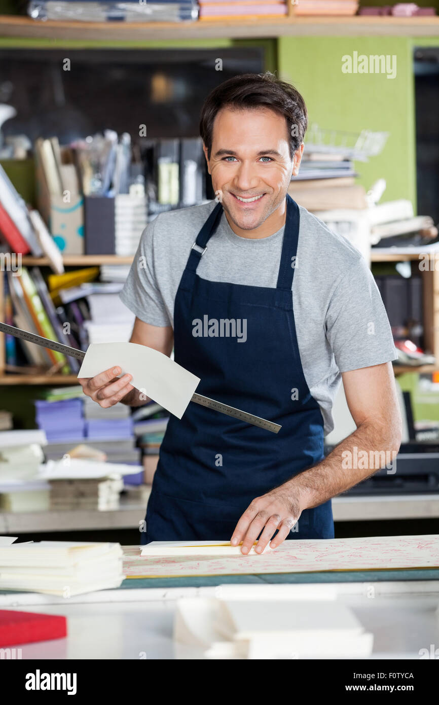 Smiling Worker Working At Table In Paper Industry Stock Photo