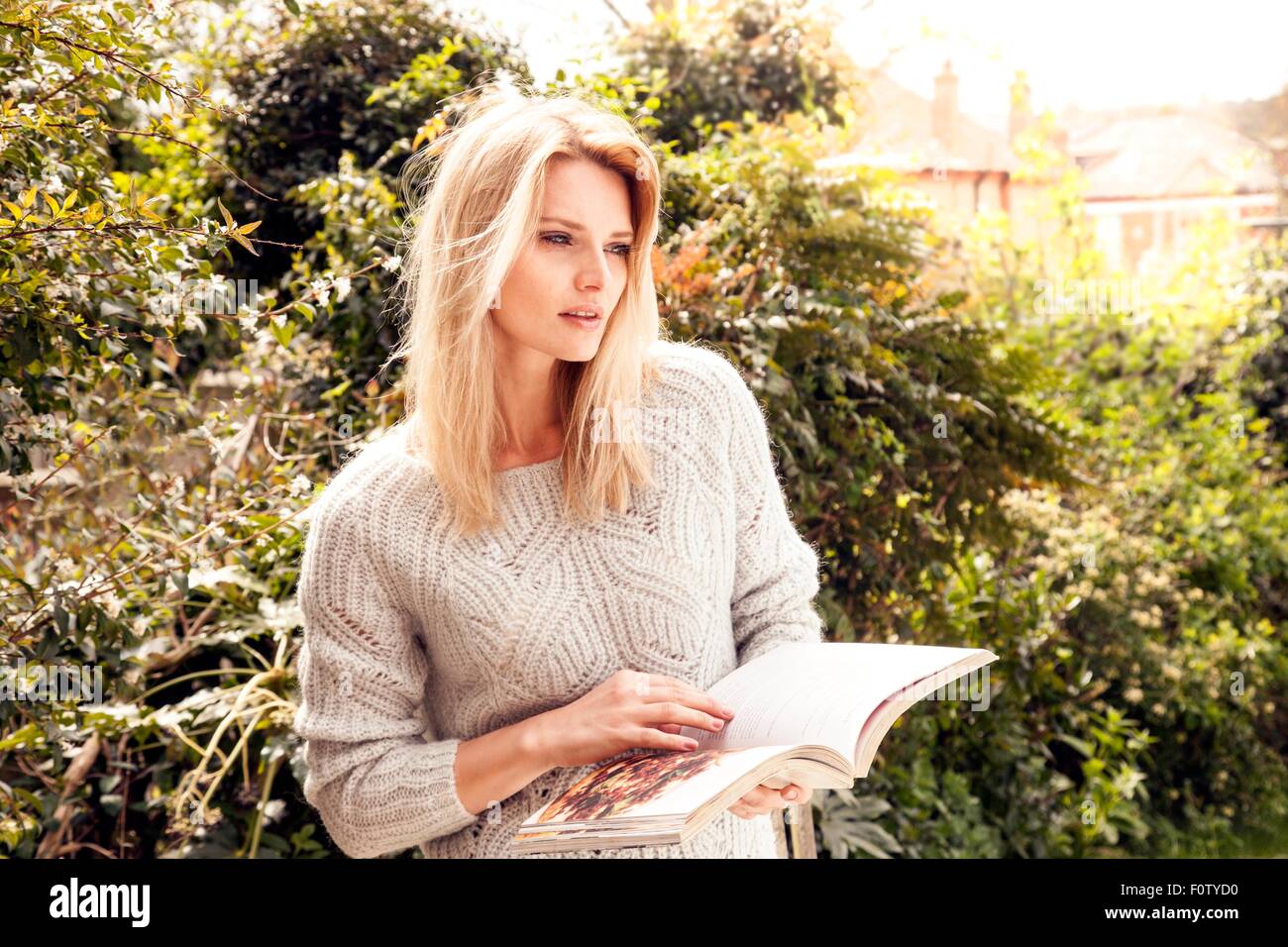 Mid adult woman in garden reading cookery book Stock Photo
