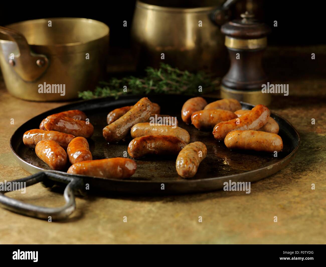 Rustic still life with fried cocktail sausages in metal serving dish Stock Photo