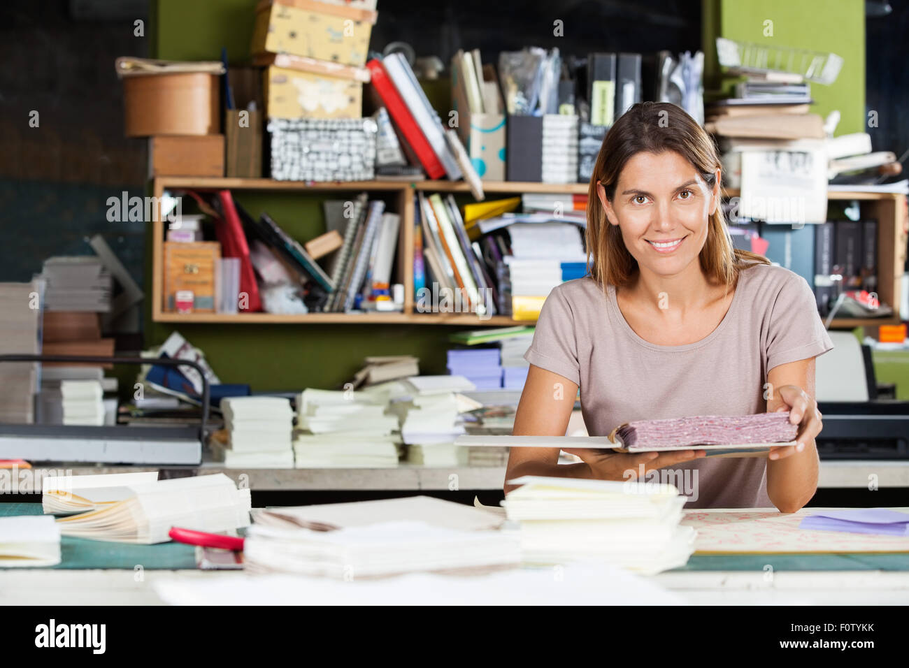 Confident Female Worker Holding Spiral Book In Factory Stock Photo