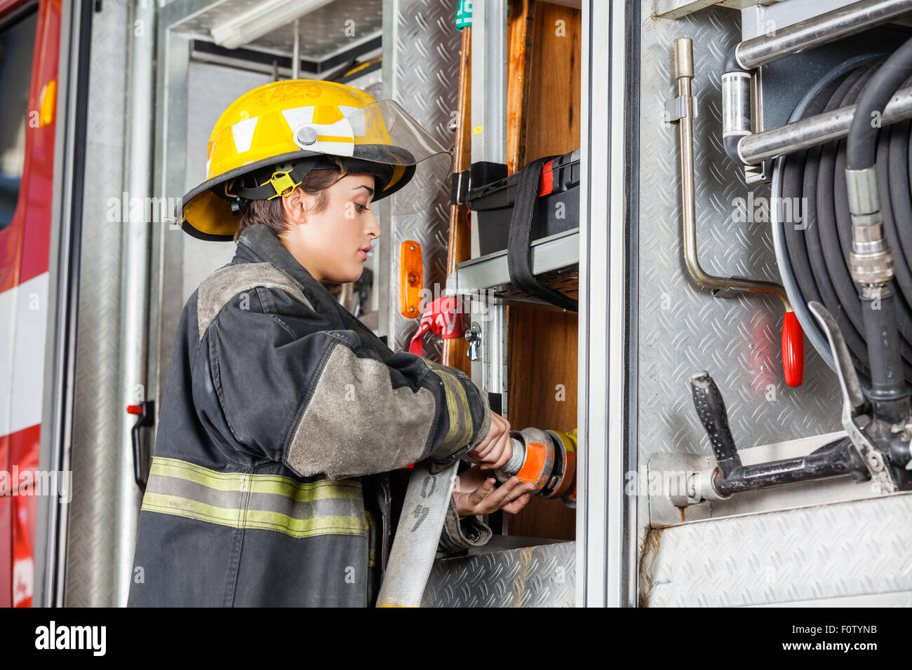 Female Firefighter Fixing Water Hose In Truck Stock Photo Alamy