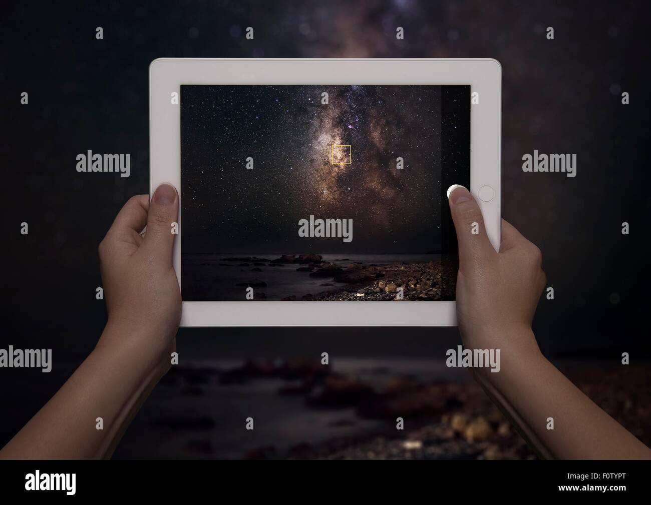 Hands of young woman holding up digital tablet with view of milky way in front of view of milky way at night, Crete, Greece Stock Photo