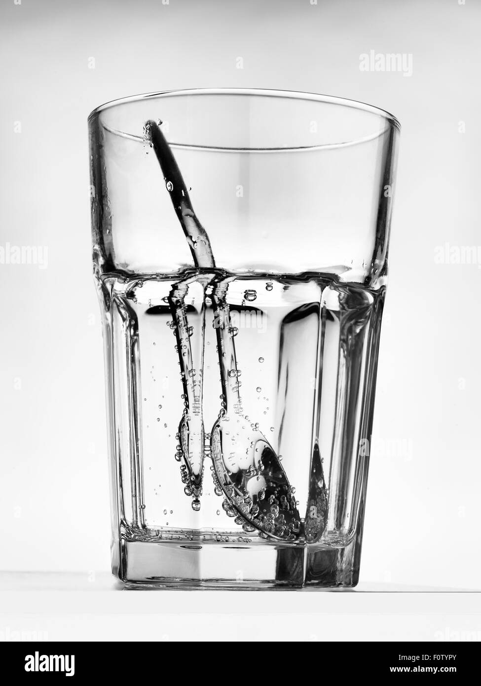 Still life of silver teaspoon inside glass of water Stock Photo
