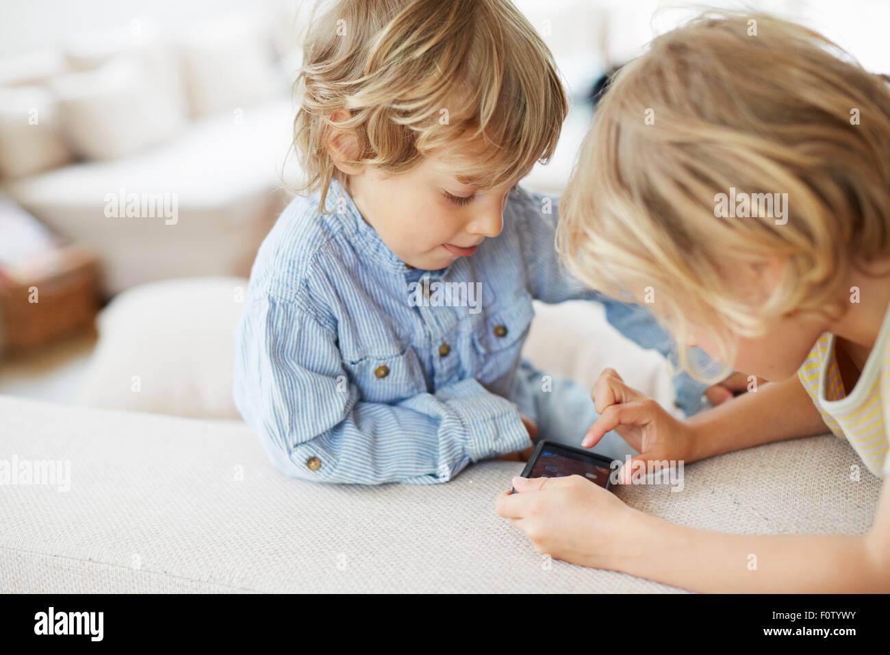 Two young brothers looking at smartphone, touching screen Stock Photo