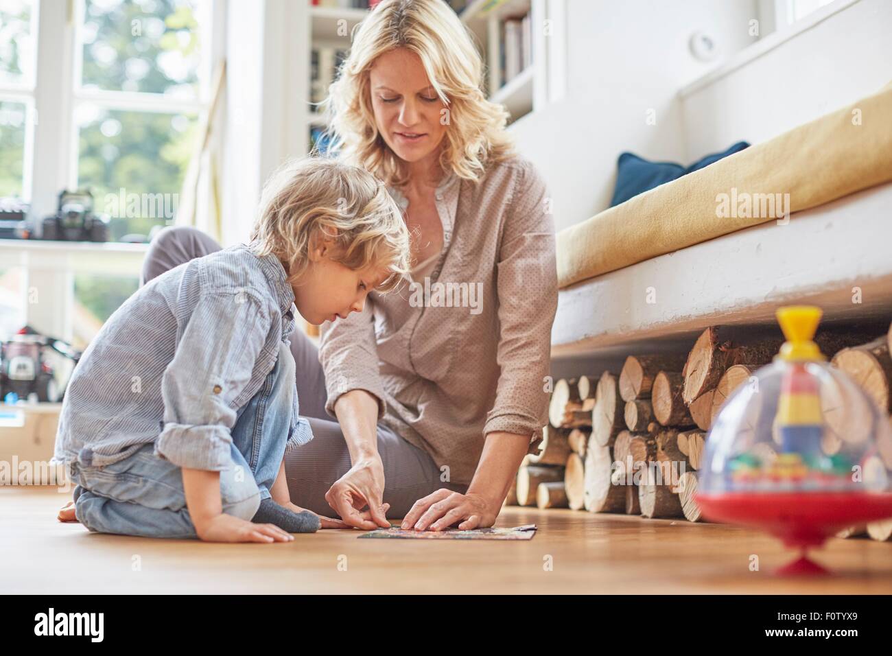 Mother and son sitting on floor, doing puzzle together Stock Photo