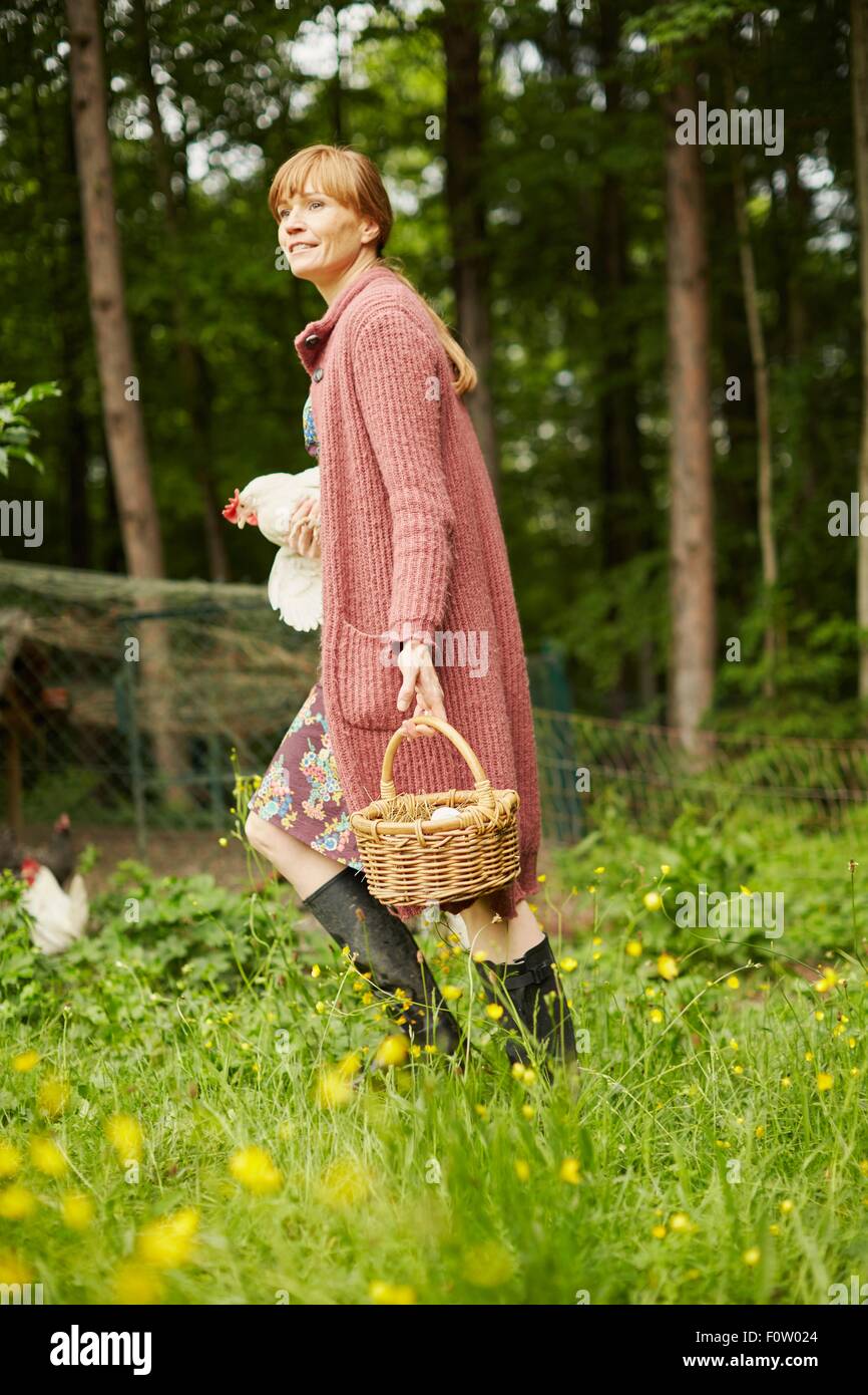 Woman carrying hen and egg basket Stock Photo