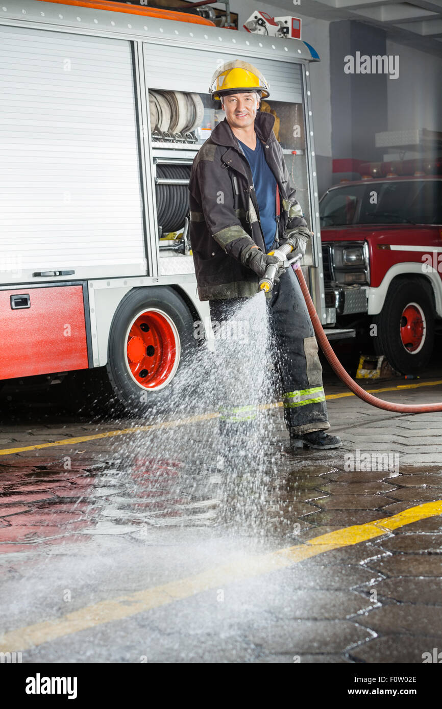 Smiling Fireman Spraying Water During Training Stock Photo