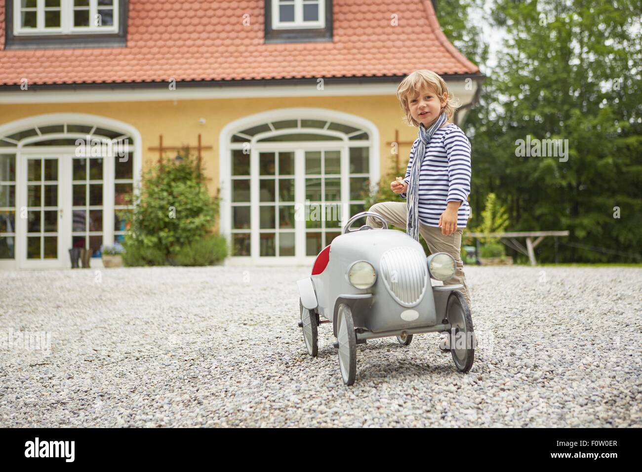 Boy playing with vintage toy car in front of house Stock Photo