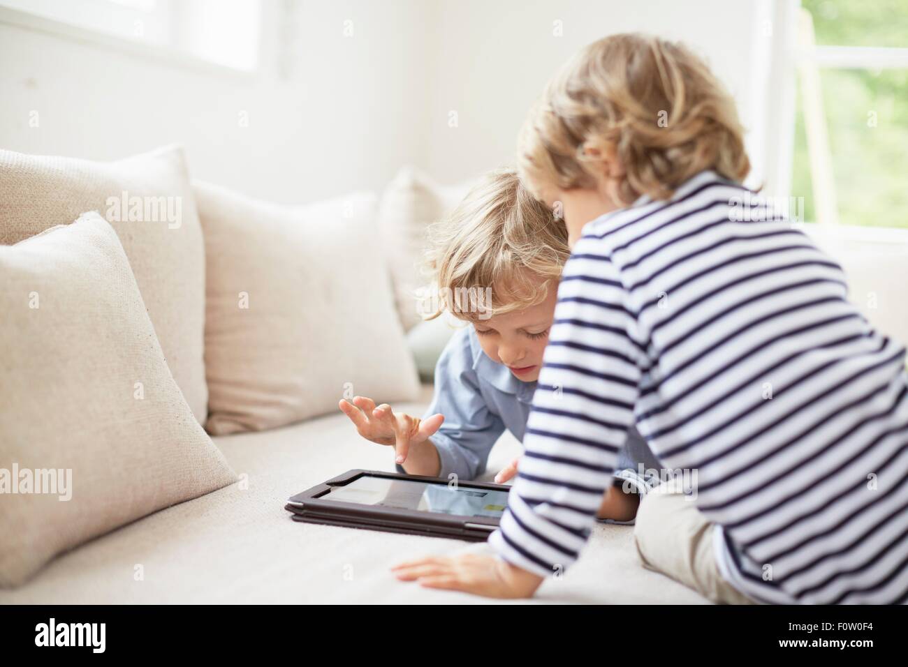 Two boys sitting on sofa using digital tablet Stock Photo