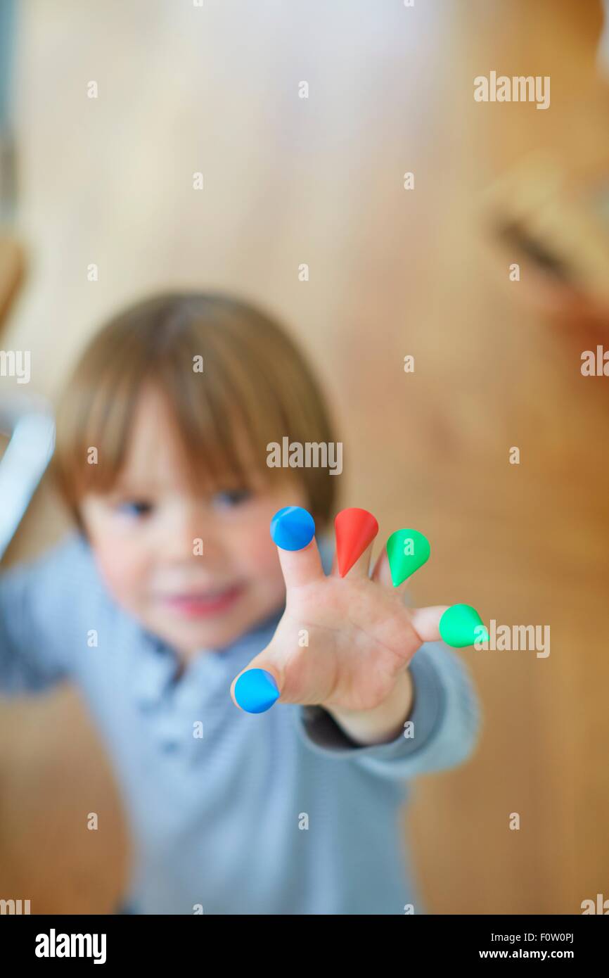 Close up of boys hand with bright coloured cones on fingers Stock Photo