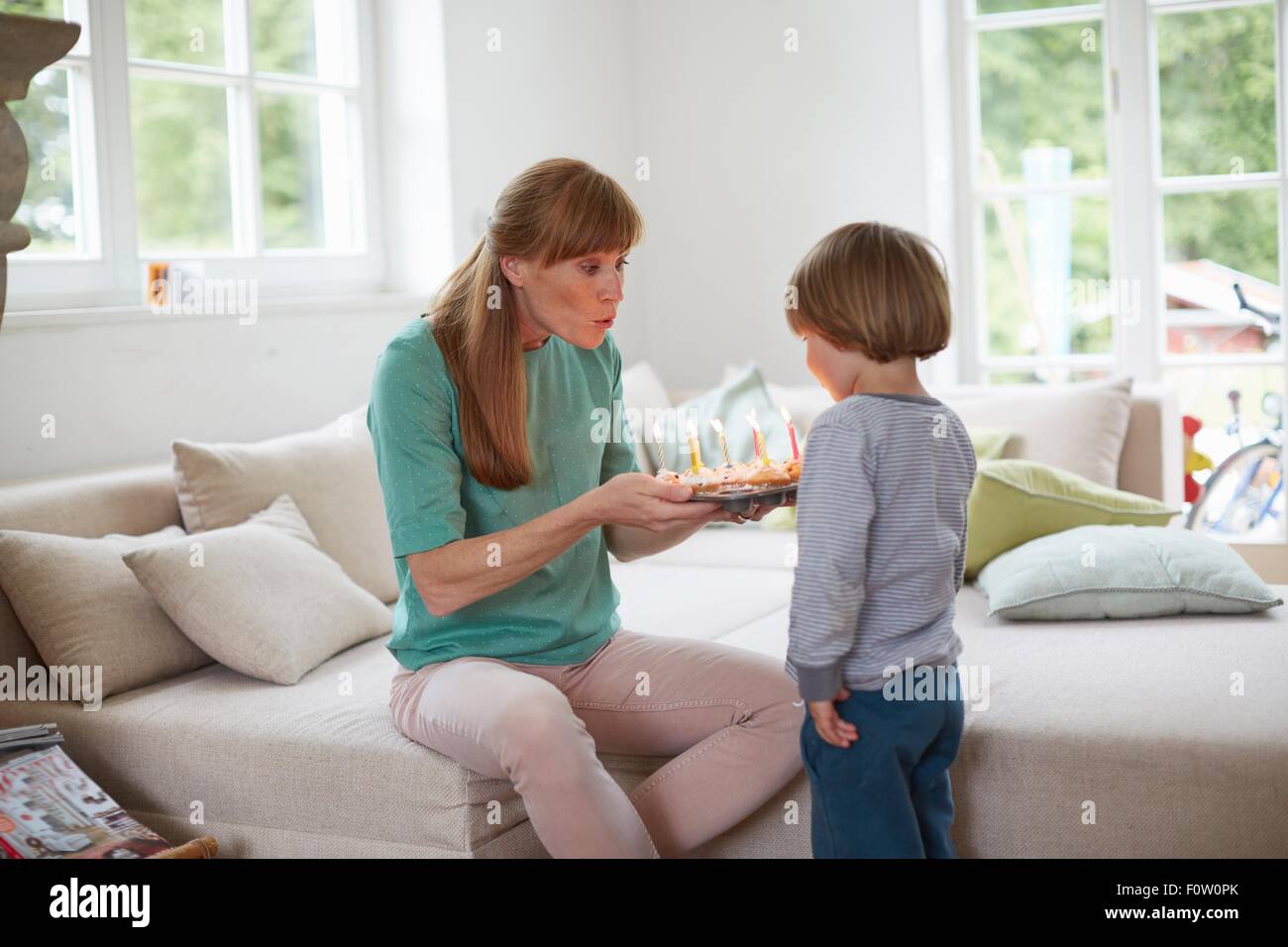 Boy and mid adult woman blowing out birthday candles Stock Photo