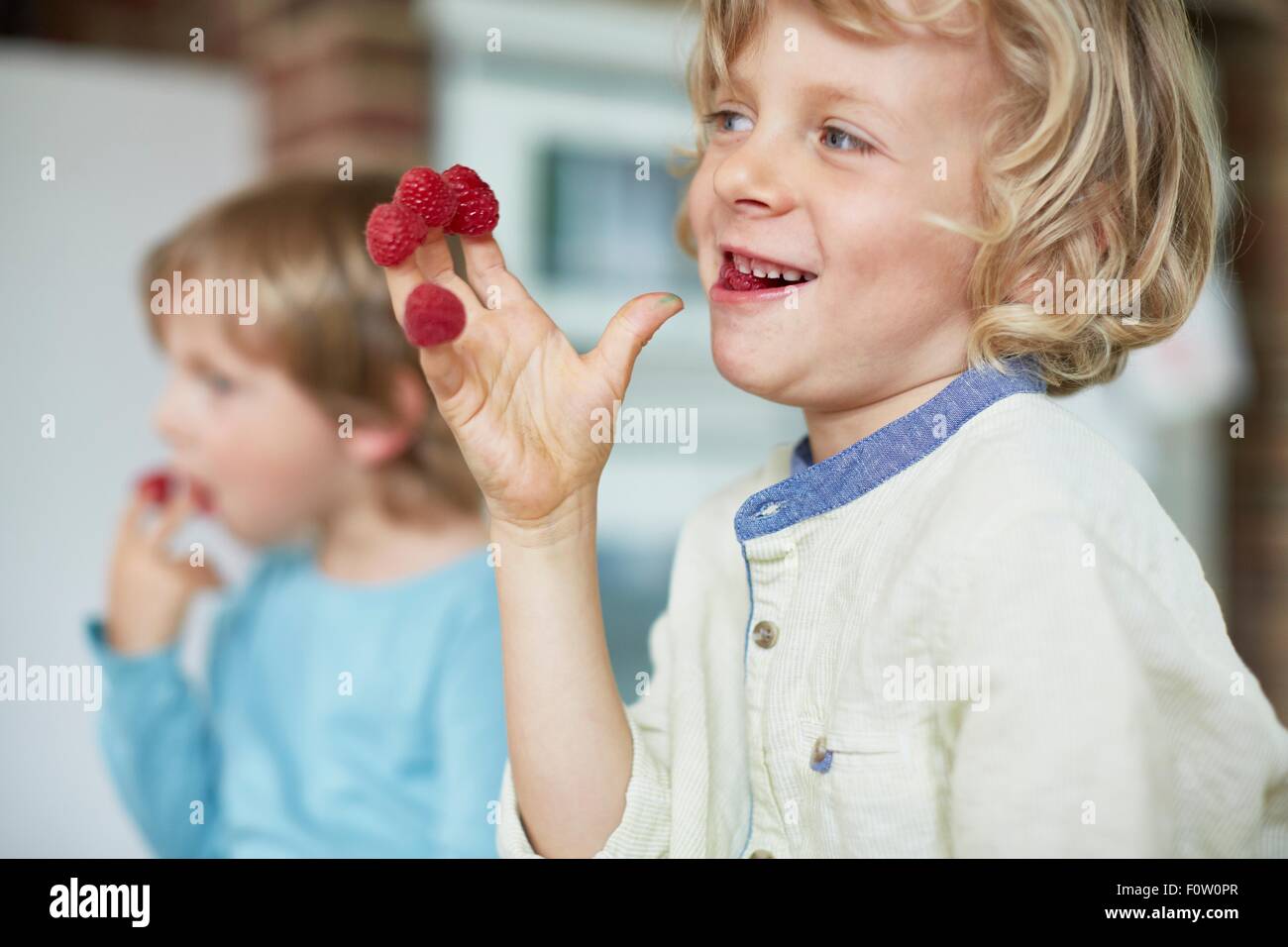 Two boys eating raspberries off fingertips Stock Photo
