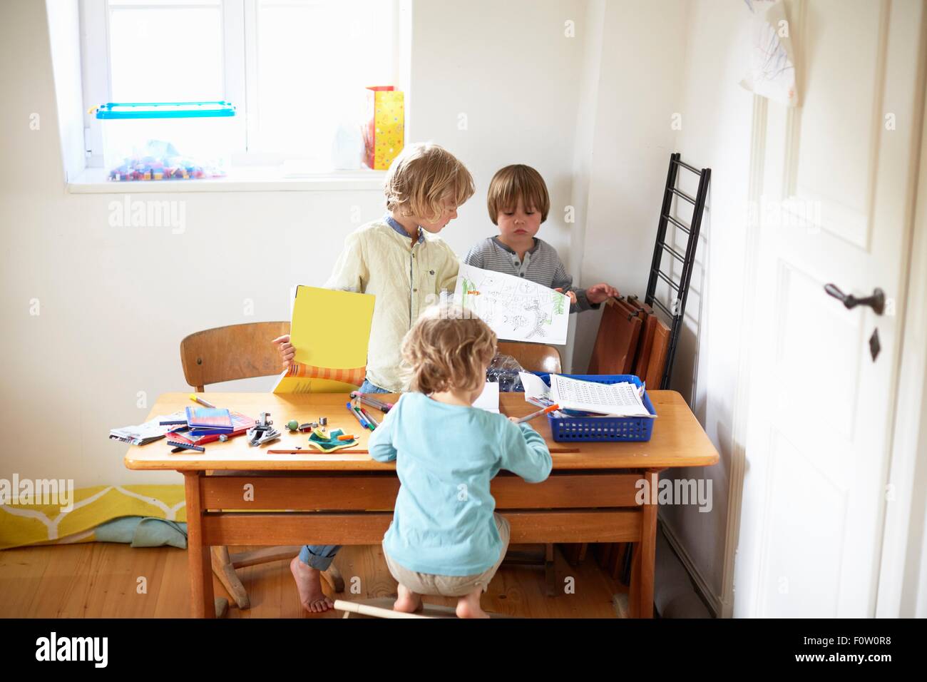 Three boys sitting at table drawing pictures Stock Photo