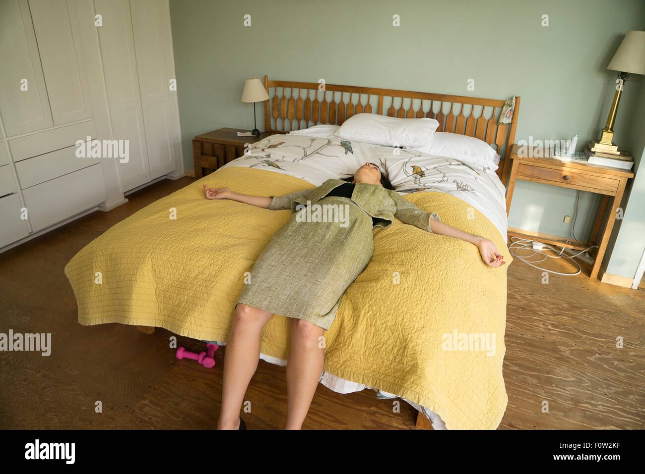 Mid adult woman lying on bed with arms open Stock Photo