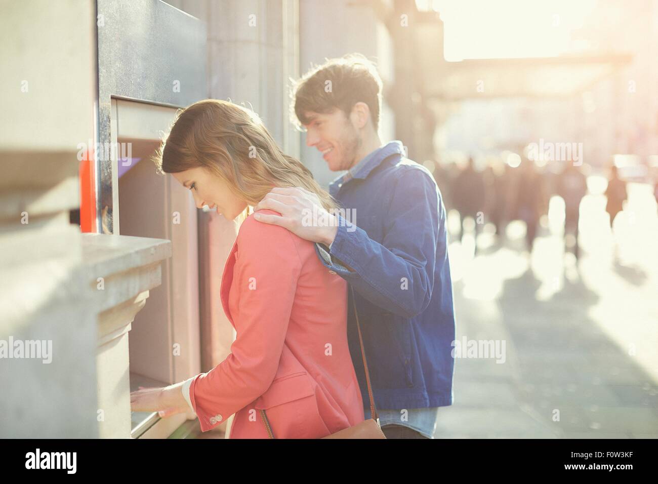 Couple withdrawing money from cash machine on street, London, UK Stock