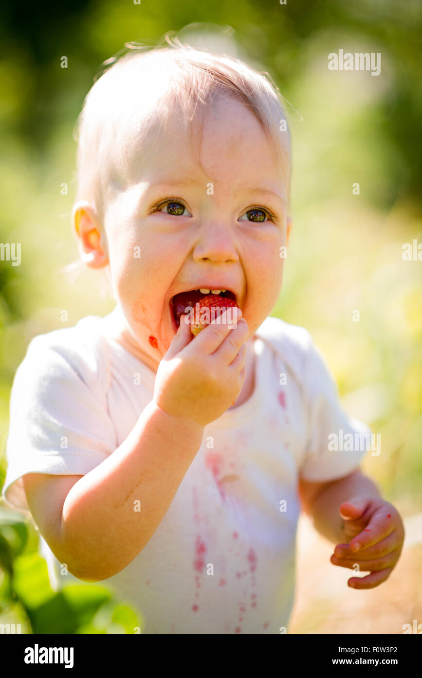 Happiness cute baby eating strawberries, outdoor in garden Stock Photo Alamy