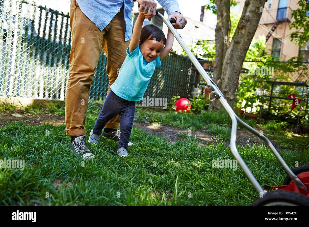 Father and son mowing lawn Stock Photo