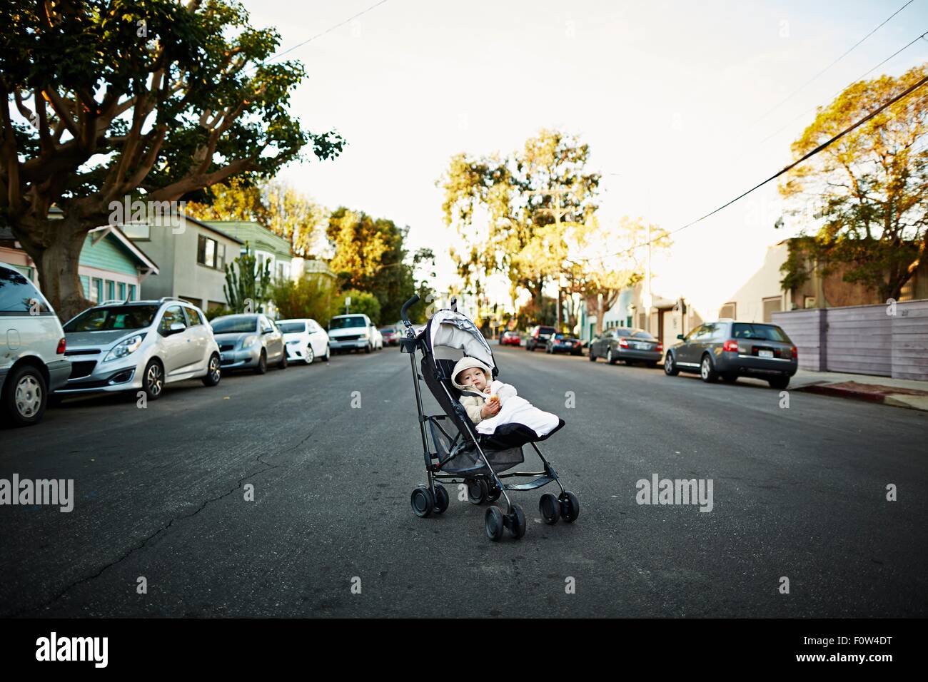 Baby boy in carriage on middle of road Stock Photo