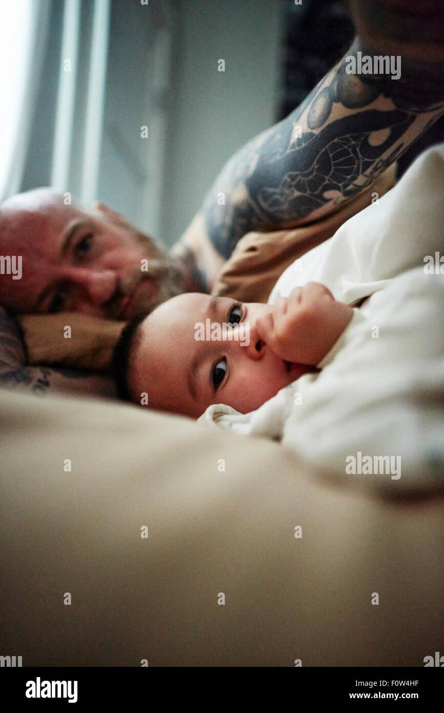 Father and son lying down on bed Stock Photo