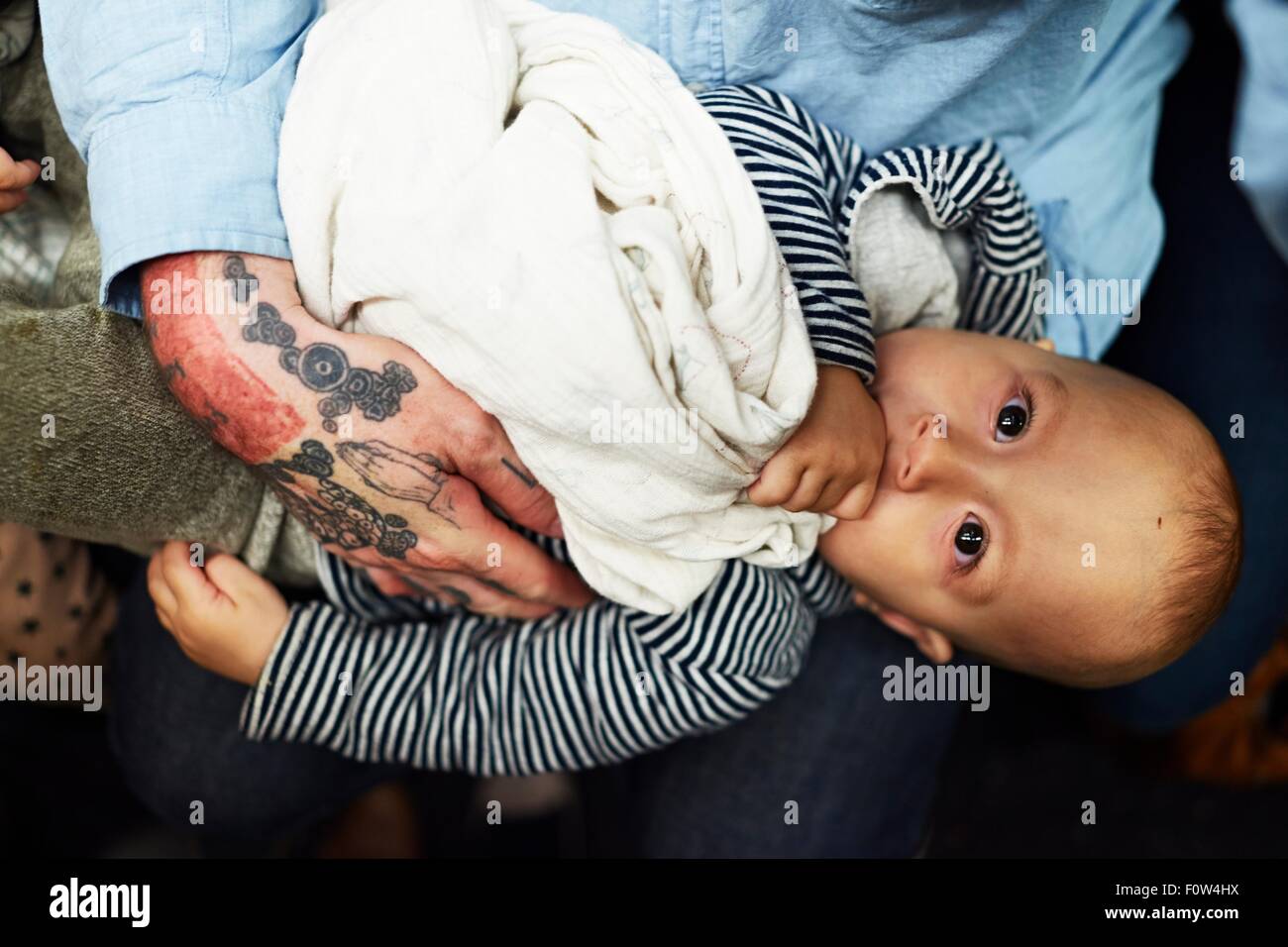 Baby boy lying down on father's thighs Stock Photo