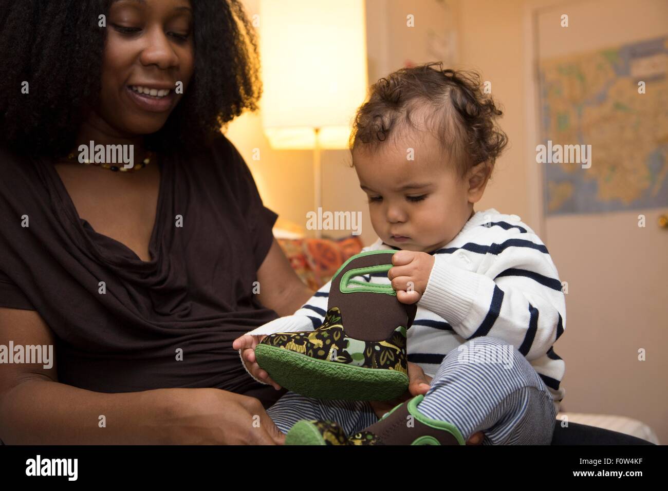 Mid adult woman and curious toddler daughter with baby boot Stock Photo