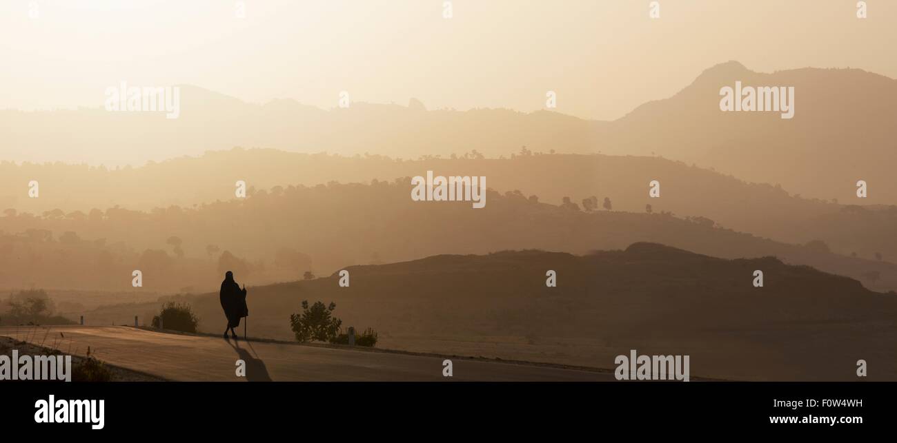 Rear view of senior man in traditional clothing looking out over landscape at sunset, Ethiopia, Africa Stock Photo