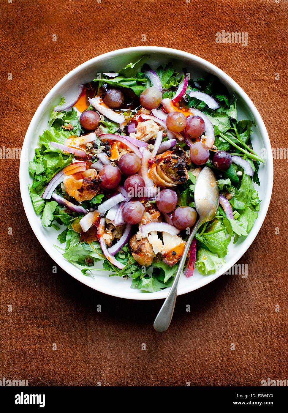 Bowl of mixed salad with red onion and black grapes Stock Photo