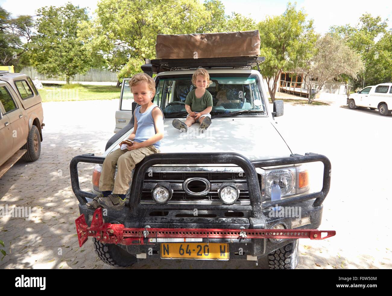 Portrait of two young boys sitting on off road vehicle, Otavi, Etosha, Namibia Stock Photo