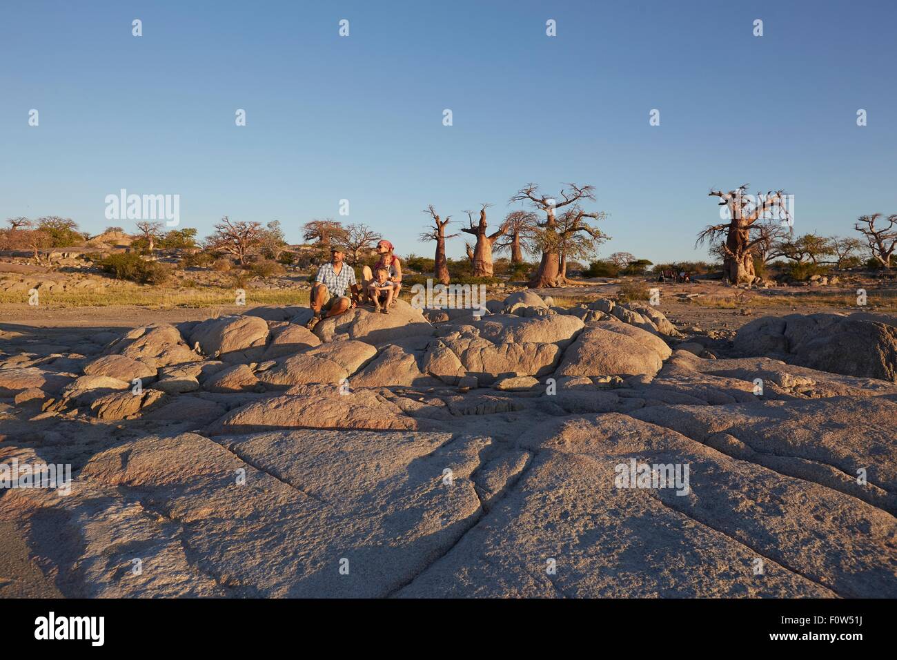 Family sitting on rocks, looking at view, Gweta, makgadikgadi, Botswana Stock Photo